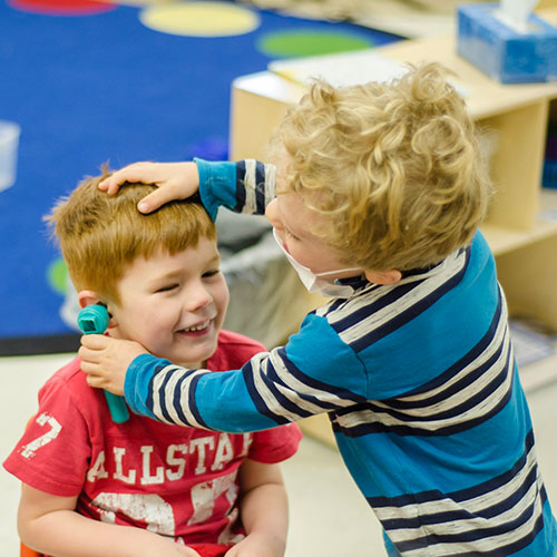 Children playing at giving an ear exam