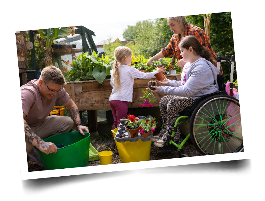 1 middle-school child in a wheelchair, 1 elementary child, and 2 adults garden outdoors together